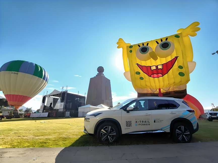 Globos aerostáticos coloridos flotando sobre Ciudad Mitad del Mundo con vehículos Nissan X-Trail e-POWER en primer plano durante festival