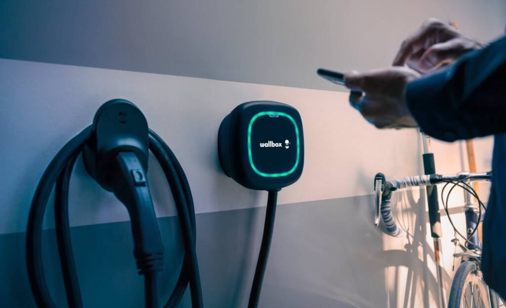 Tecnología clave para cargar autos eléctricos mediante sistema Wallbox instalado en estación de carga moderna.