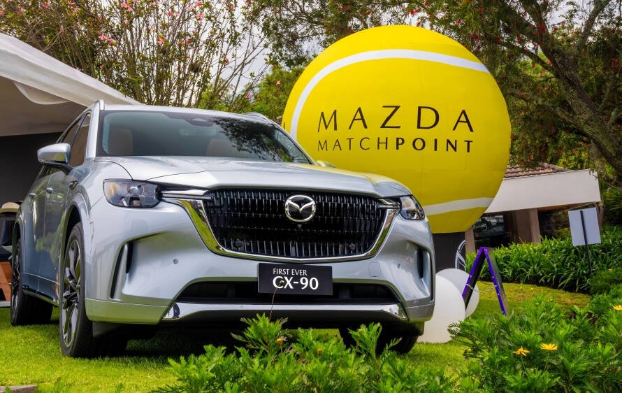 Jugador de tenis ecuatoriano celebrando victoria en Copa Davis con logo Mazda Match Point de fondo (