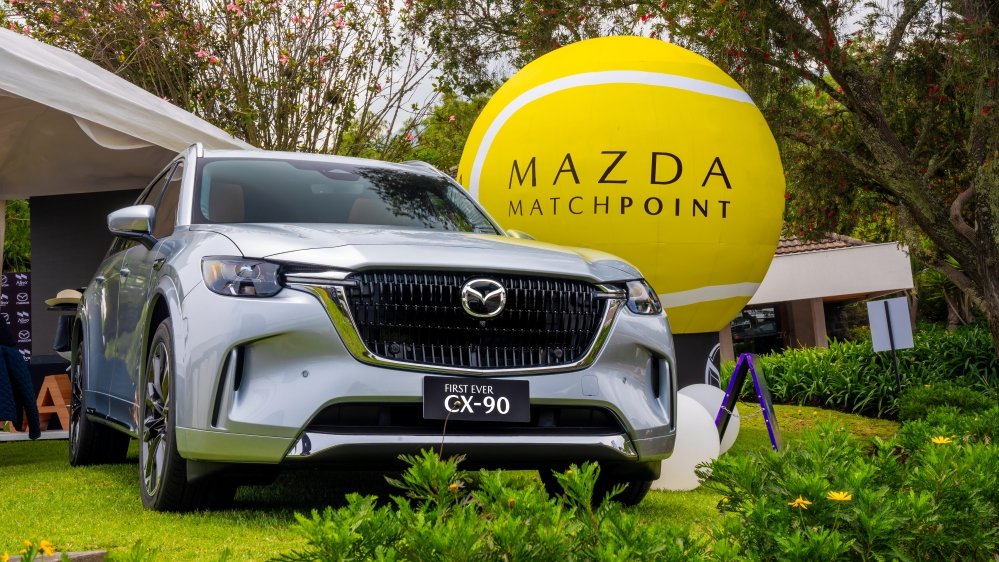 Jugador de tenis ecuatoriano celebrando victoria en Copa Davis con logo Mazda Match Point de fondo (
