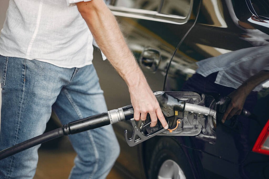 Conductor revisando la presión de sus llantas para gastar menos combustible de manera eficiente en una estación.