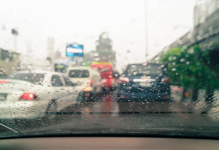 Vehículos circulando bajo lluvia intensa en vía urbana de Ecuador — siniestros viales en temporada invernal