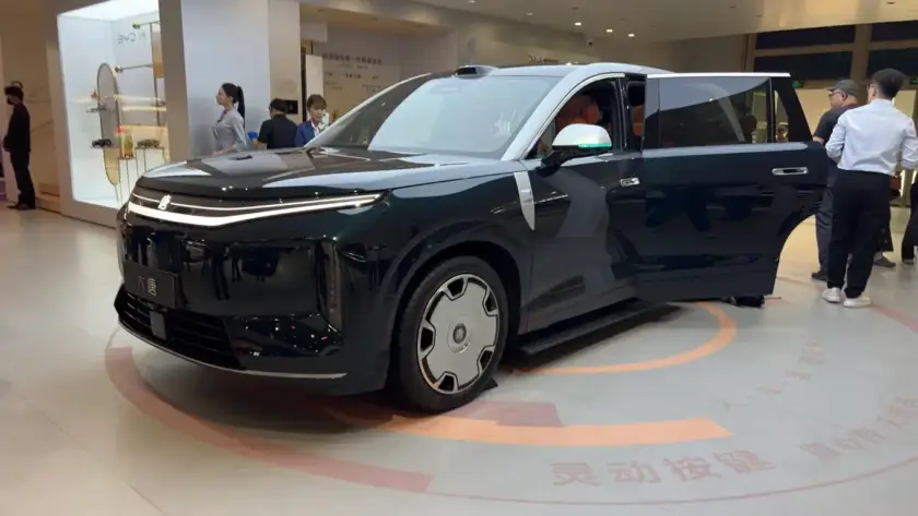 Una fila de SUV chinos grandes y modernos, con diseños aerodinámicos y faros LED brillantes, estacionados en un salón de exhibición con un ambiente futurista. Se aprecia el tamaño imponente y la sofisticación de los vehículos.