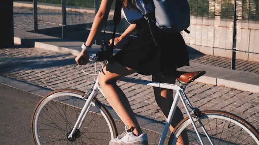 Persona pedaleando en bicicleta por una calle urbana con árboles, representando movilidad sustentable en bicicleta