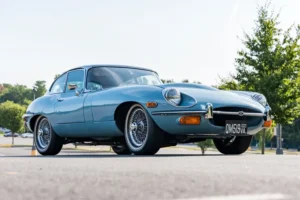 Deportivo clasico azul claro en un evento donde Bring a Trailer subasta un Jaguar E-Type Series II
