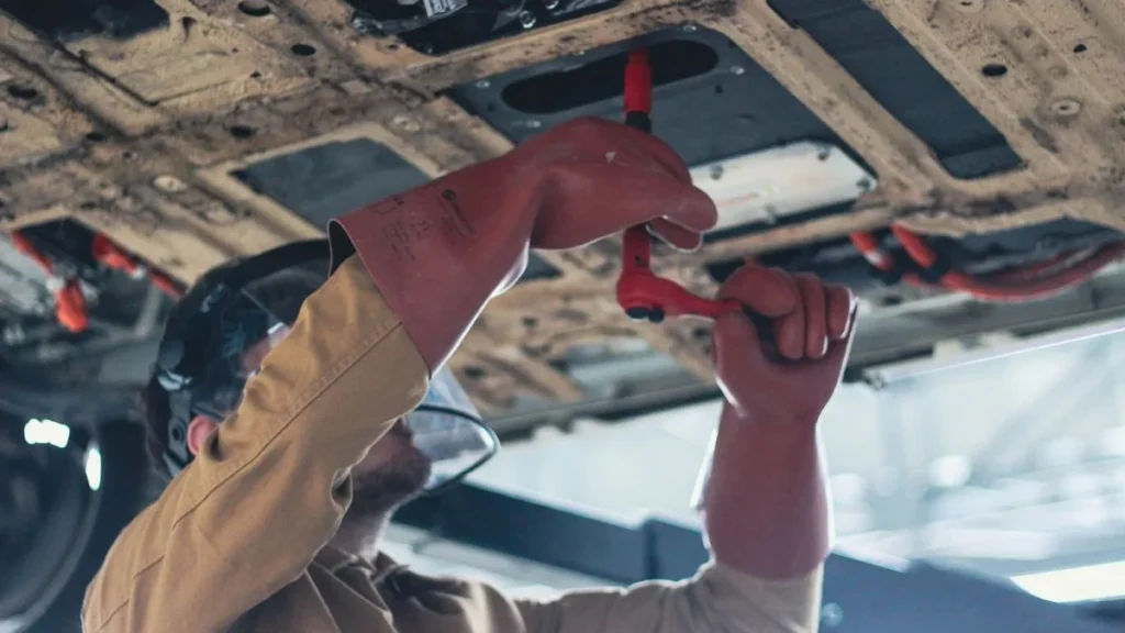Técnico automotriz realizando diagnóstico electrónico en un taller de vehículos eléctricos